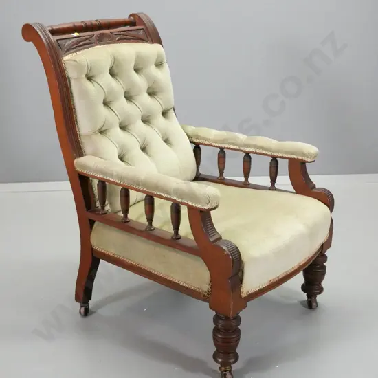 Edwardian gent's chair with carvedframe, spindles on arms, in deep-button green velvet, original porcelain casters