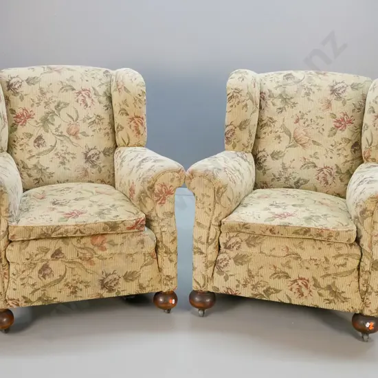 pair of vintage chesterfield style rolled-arm wing-back lounge chairs w/ ball feet, metal casters, covered in floral