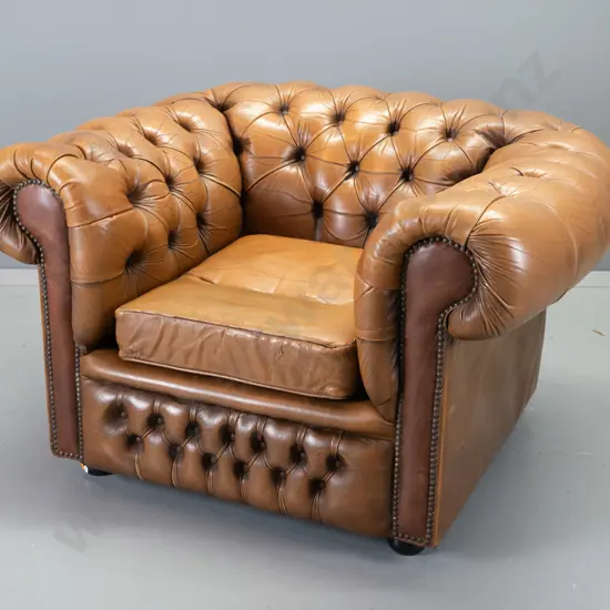deep-button rolled arm chesterfield style chair w/ball feet, covered in antiqued-finish leather, surface cracking to