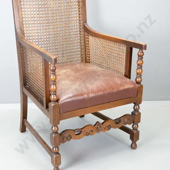 oak-framed Tudor style occasional chair with bergere cane back and sides, leather upholstered seat, carved front rail.
