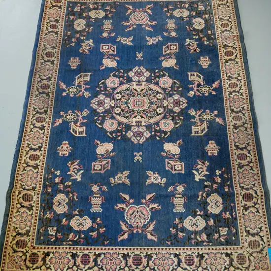 blue ground oriental rug, floral central medallion surrounded by floral decoration, pink and blue floral border