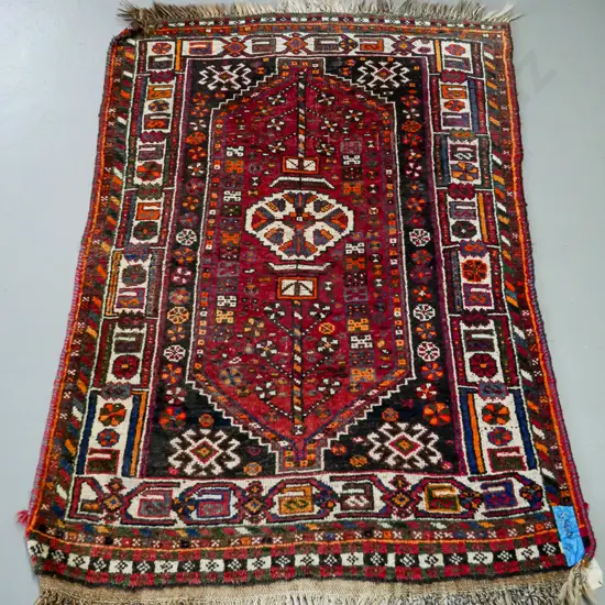 handknotted Iranian rug, central geometric motif, in reds blues and saffron, geometric border