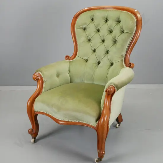 Victorian gent's mahogany framed lounge chair with deep button back, carved front legs, porcelain casters, green velvet