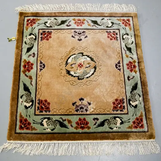 oriental rug, central medallion of two cranes, brown tonings, green border of cranes and flowers and mythical clouds