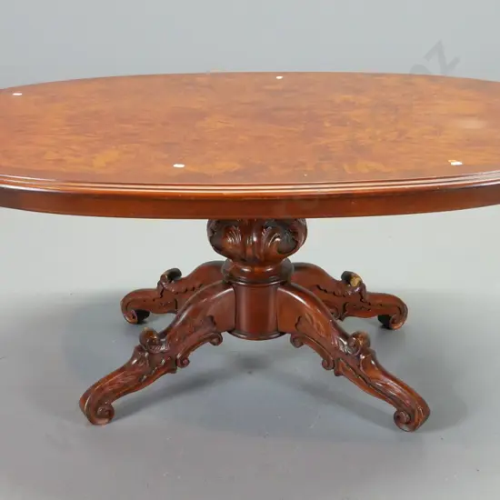 reproduction walnut oval coffee table with cross-banded edge, on carved 4-point pedestal base - wear to base H560 L1300