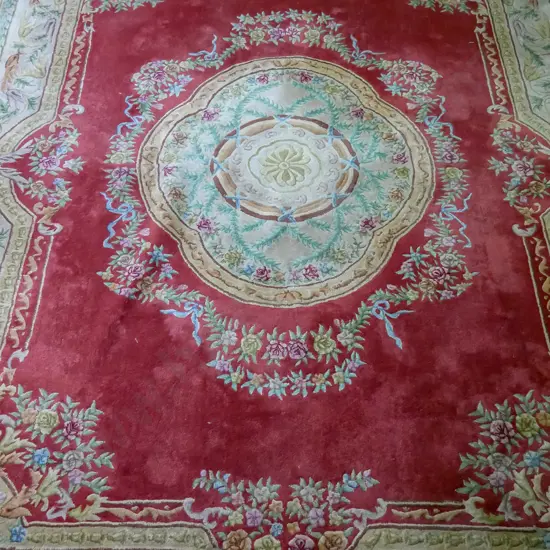 large woollen Asian floor rug, red ground, scalloped central medallion with foliate border