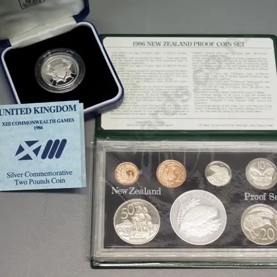 2 cased coins sets - New Zealand 1986 proof set and cased UK 1986 Commonwealth Games 2 pound proof - booklet mentions 2