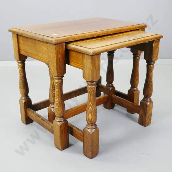2 vintage oak nesting tables on turned bolster legs - wear to polish on both tops. Larger H-480 W-560 D-350