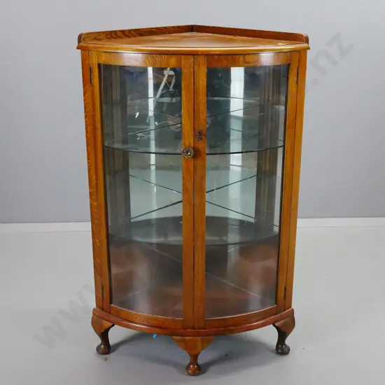 vintage oak corner display case with 2 bowed glazed doors, 2 glass shelves, 3 short cab legs. Working lock & key.