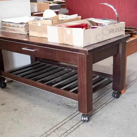 dark stained coffee table with single and plastic casters - varnish needs attention