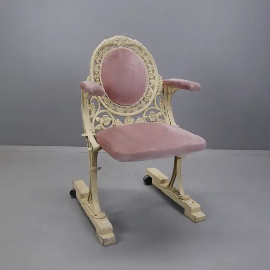 cast metal flip-up theatre seat on wooden base with casters on the back, salmon pink upholstery, ex St James