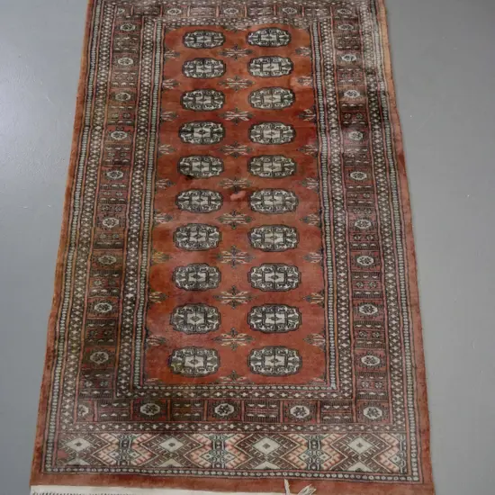 Persian style hand knotted floor rug - terracotta and light browns, some fading, staining on end L-1650 W-930