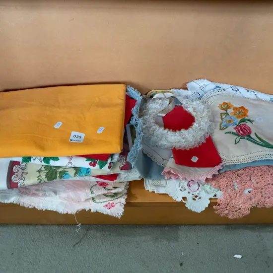 shelf of hand worked linen table cloths etc.