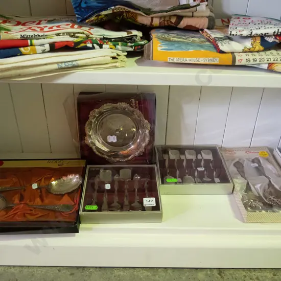 shelf of cased cutlery and a plated bowl