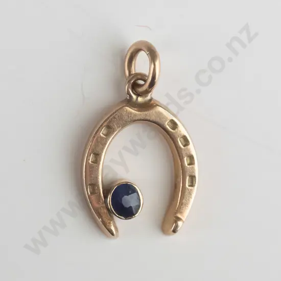 9ct gold horse shoe charm with small oval blue stone in rubover setting