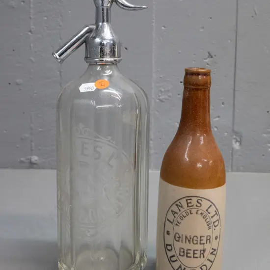 2 Lane's Dunedin items - salt-glazed ginger beer bottle and a soda syphon with chrome top marked Lane's H-300 D-100