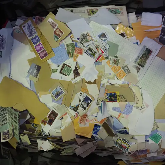 black plastic container quarter filled with loose stamps