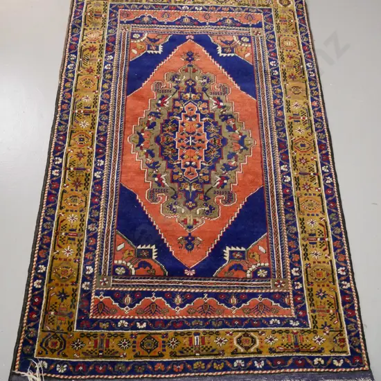 Persian style hand knotted wool floor rug - multi coloured on dark blue and red ground. Fringe mostly gone from one end.