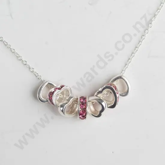 silver necklace with 7 small hearts 3 with pink stones stamped 925