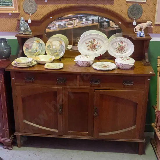 art nouveau sideboard with oval bevelled edge mirror in top, 2 small shelves, 2 drawers over 2 cupboard doors, foliate