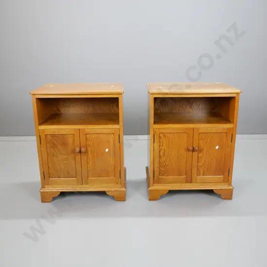 pair of oak traditional style bedside cabinets with 2 panelled doors w/wooden knobs, bow front top, on bracket feet.