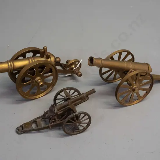 3 metal model cannons - 2 brass and a small cast metal Britains England. Largest is H-85 L-180