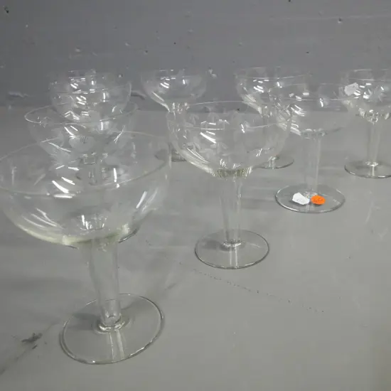 9x hollow-stemmed champagne glasses, etched floral decoration around bowl. H-120