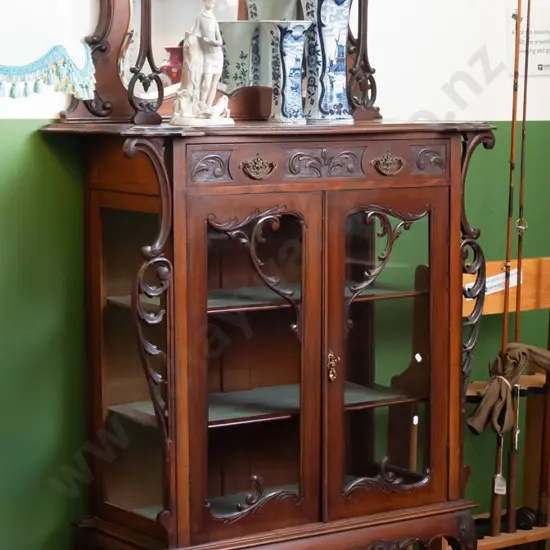 art Nouveau walnut parlour display case, pierced and carved pediment above shaped bevel edged mirror,