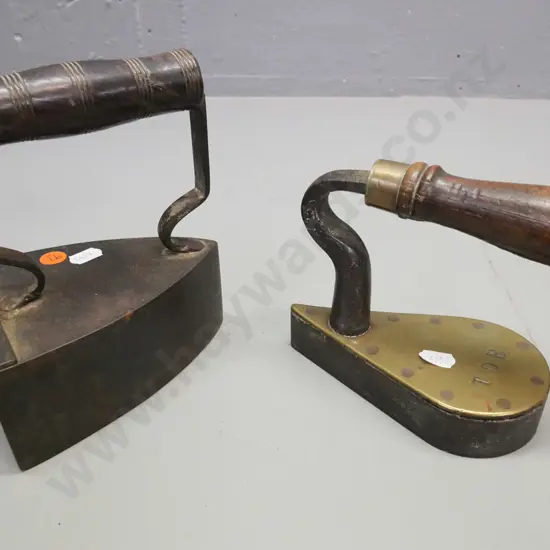 2x vintage cast metal irons with turned wooden handles. 1. Larger w/ coal box, shutter. 2. Small flat iron stamped TDB