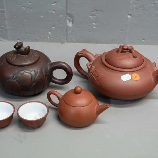 3 Chinese Yixing clay tea pots and 2 small tea bowls, one with leaf & tree forms has small chip in underside of lid, is