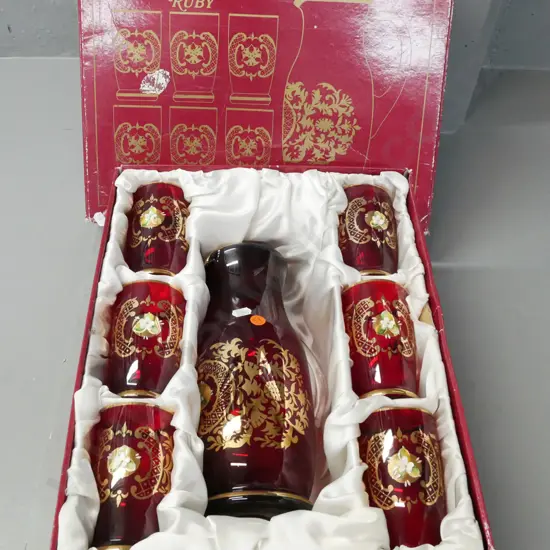 fitted box of Bohemian Ruby Glass set of carafe and 6 tumblers w/ gilded and raised enamel decoration. Jug H-260