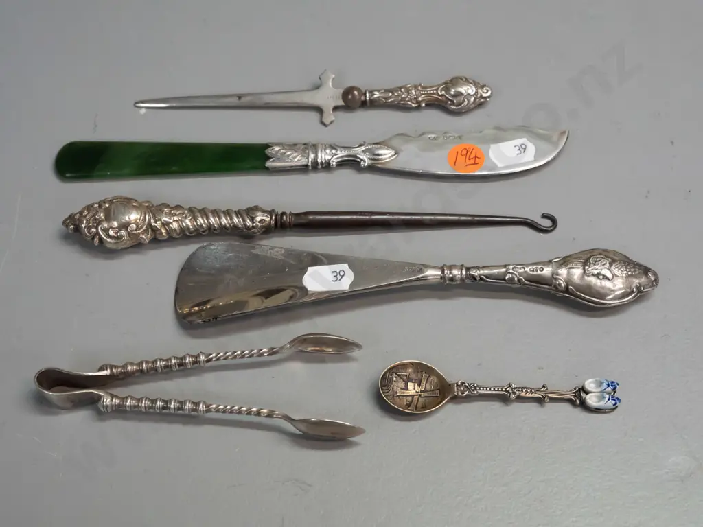 6 cutlery items, 4 hallmarked sterling silver, one knife with greenstone handle, plated sugar tongs and Dutch spoon. Image 1++