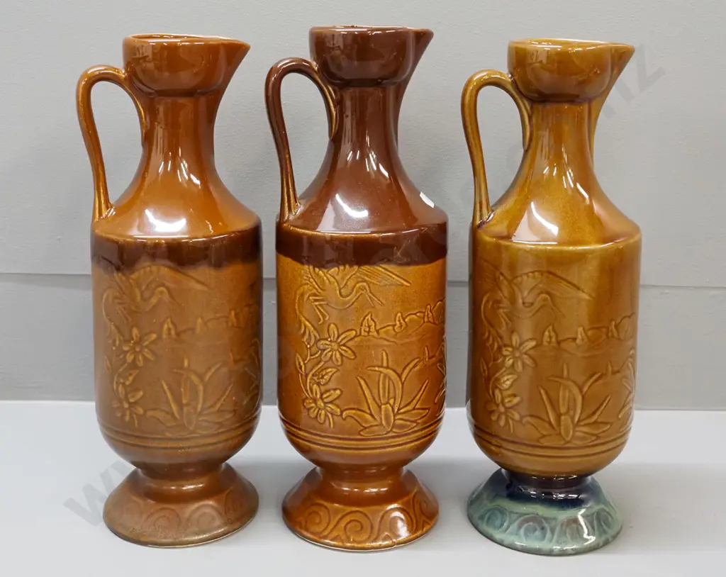 3 Orzel pottery NZ handled ewer jugs with raised floral and crane motifs - one has under-glaze fault on rim H-320 Image 1++