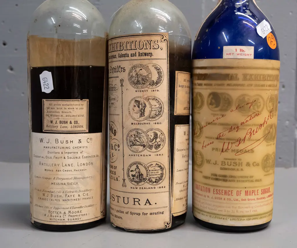 3 vintage glass bottles with labels and contents & WJ Bush & Co labels, one blue & 2 clear, metal cap seals H-250 Image 1++