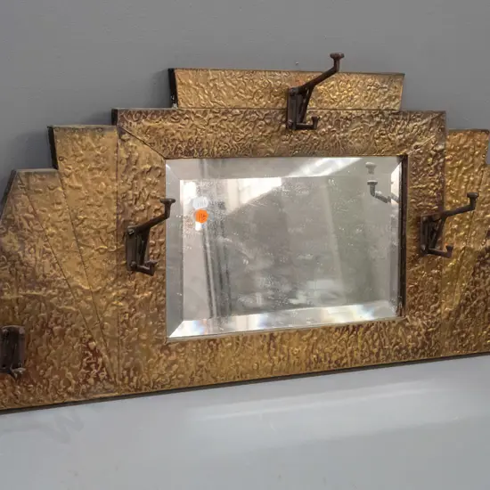 art deco beaten brass bevelled edge wall mirror with 5 hat / coat hooks. Tip broken off one hook, some desilvering.
