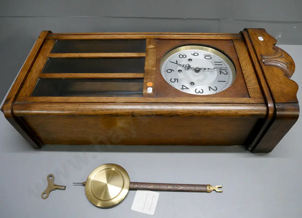 oak cased Art Deco chiming wall clock by Enfield, England. Glazed panels to door, brass pendulum and key. H-770 W-340 Image 1++
