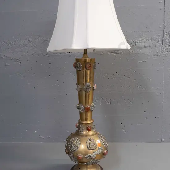 brass table lamp with applied Buddha and mythical beast decoration and inset stone or glass cabuchons - 3 are missing.