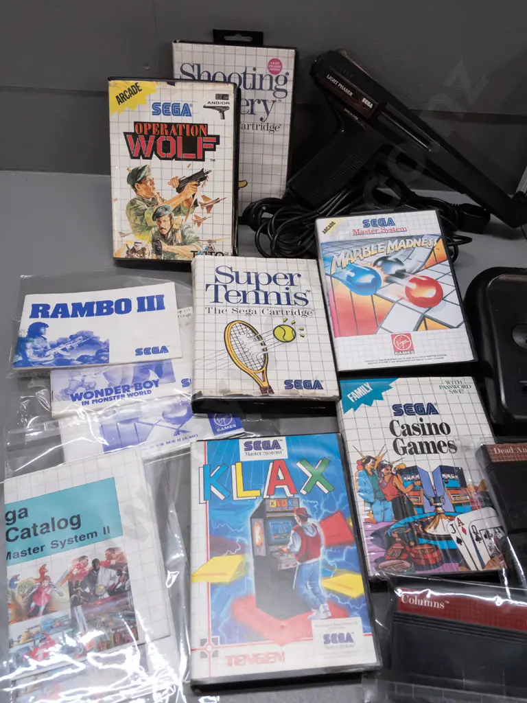 large Sega Master System II collection with 2 consoles, 2 handheld controllers, arcade pistol, numerous game cartridges Image 1++