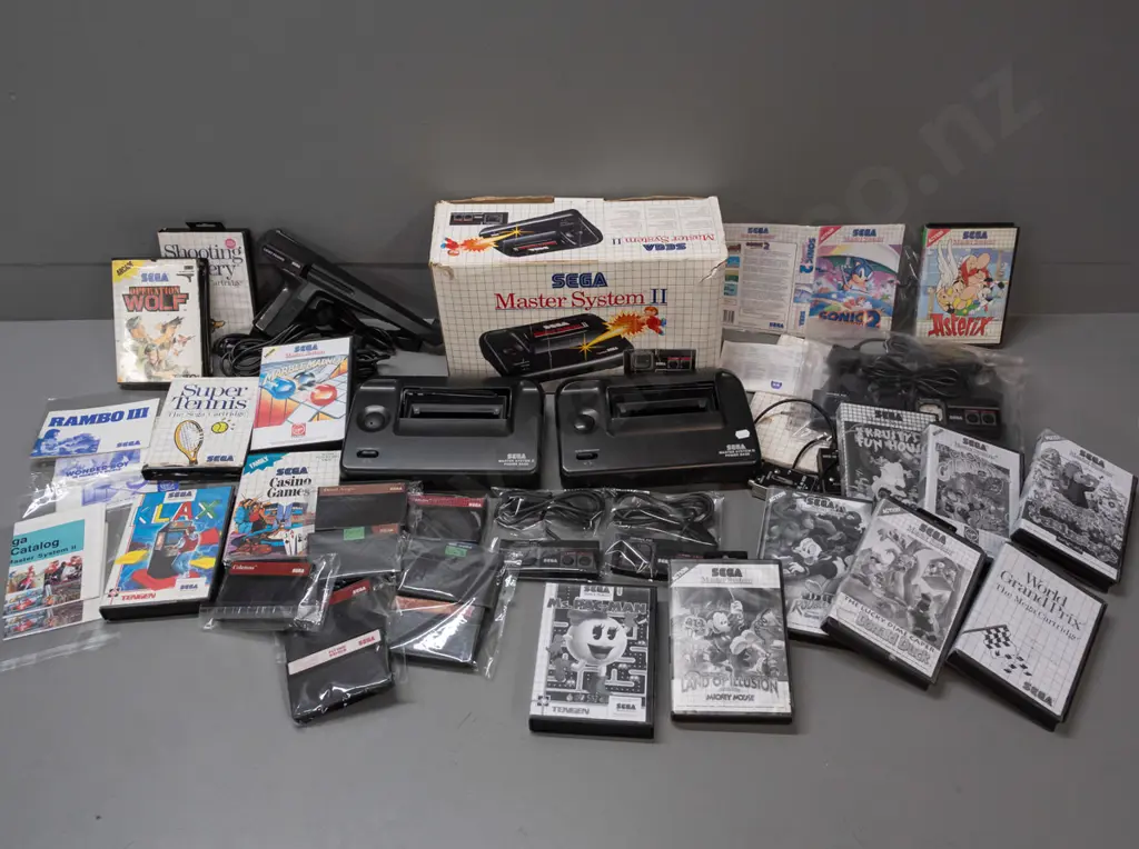 large Sega Master System II collection with 2 consoles, 2 handheld controllers, arcade pistol, numerous game cartridges Image 1++