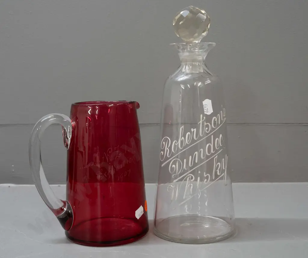 cranberry glass jug with NZI 1907 Exhibition inscription & a stoppered decanter with Robinson's Whisky Dundee in white Image 1++