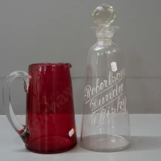 cranberry glass jug with NZI 1907 Exhibition inscription & a stoppered decanter with Robinson's Whisky Dundee in white
