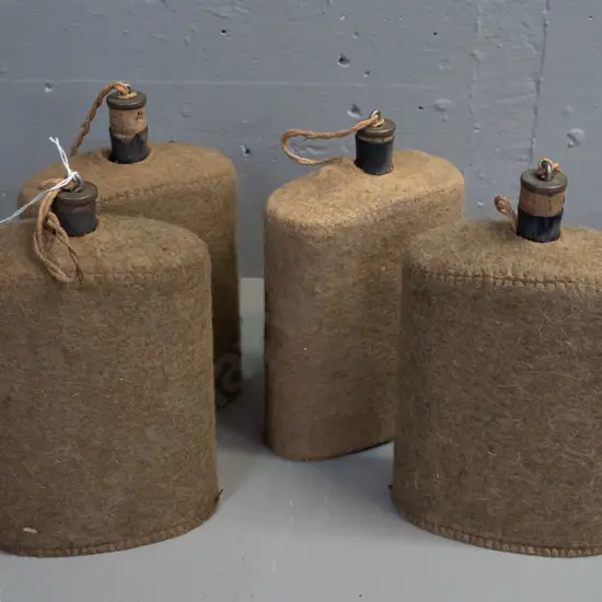 4x WWII-era enameled metal water bottles with felt covers and cork stoppers