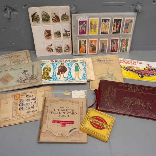 Assorted cigarette collector cards in sheets and albums, including a Wills cigarette box. Albums have partial contents