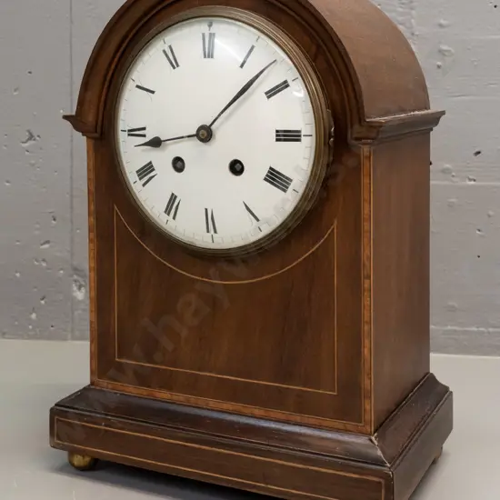 vintage wood-cased mantle clock w/ mixed timber inlay decoration, on brass ball feet. Enameled metal face. Untested
