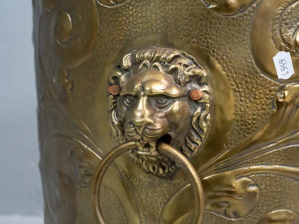 beaten brass jardiniere or wood bin with horse, windmill and heraldic motifs, with lion's head ring handles, on cast paw Image 1++