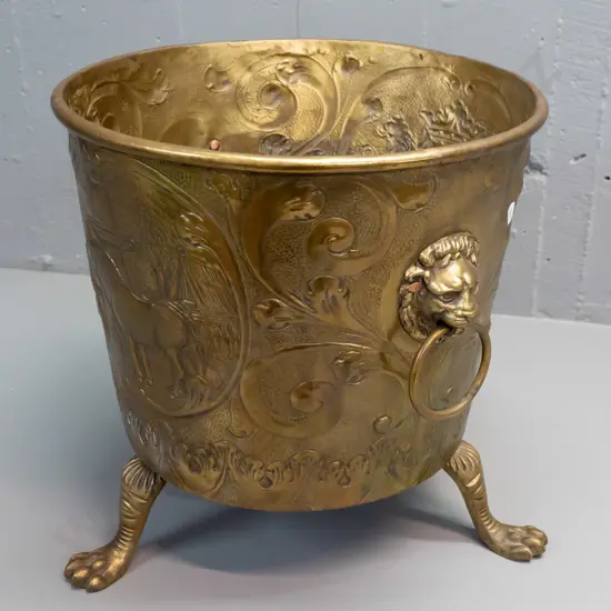 beaten brass jardiniere or wood bin with horse, windmill and heraldic motifs, with lion's head ring handles, on cast paw