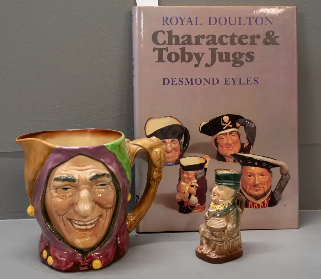 2 Royal Doulton character jugs and a book by Desmond Eyles - larger Touchstone H- 155 and smaller Mr. Micawber H-110 Image 1++