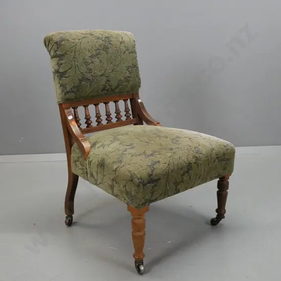 Edwardian walnut upholstered bedroom chair w/ turned gallery in back, turned legs w/ casters, green foliate upholstery,