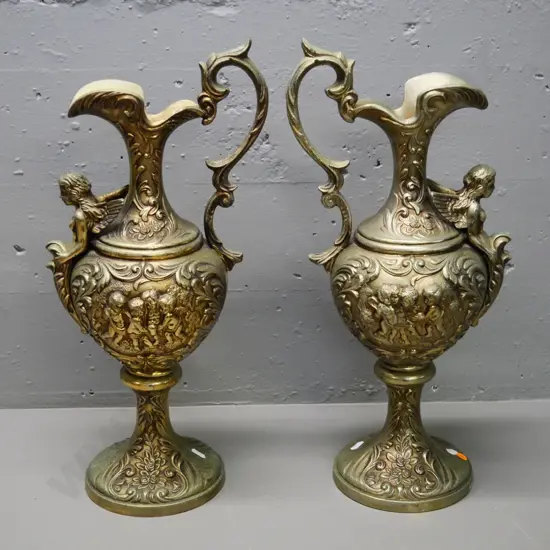pair of ornate brass finish cast metal ewer jugs with cupid and angel motifs H-500 W-230 at handle