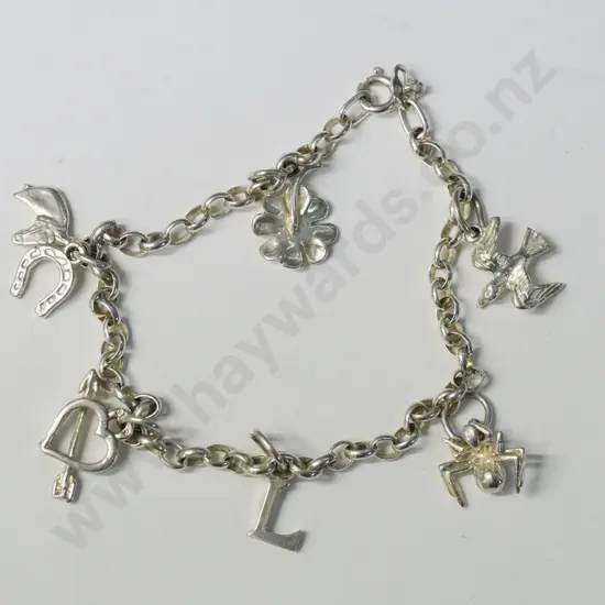 silver charm bracelet has 7 charms flower,bird,horse, horse shoe,spider,heart,letter L